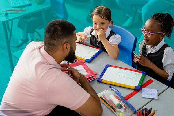 Teacher helping two students at a table